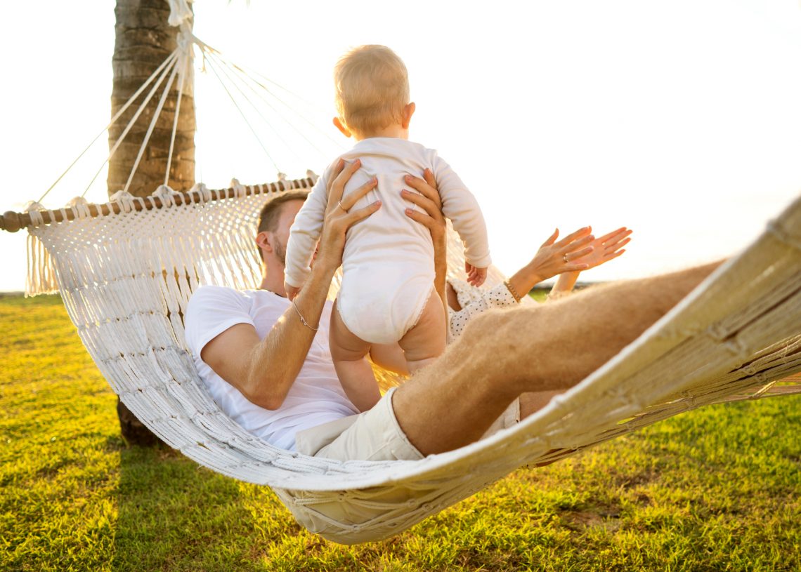 happy family on a tropical island at sunset lie in a hammock and