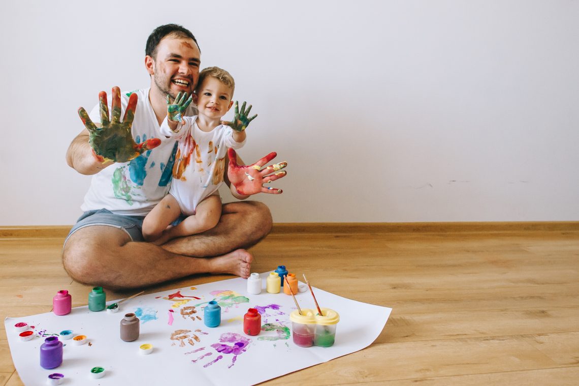 Father and little boy of fivr years having fun painting at home