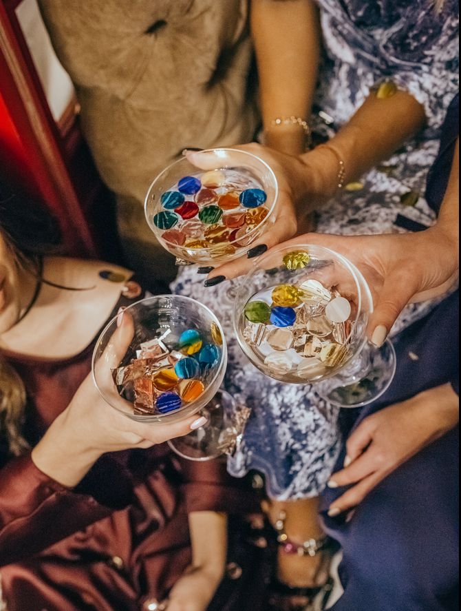 Женские руки держат бокалы с шампанским и конфетти фото