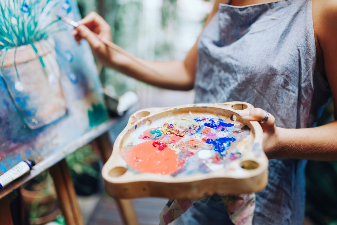 Фото женщина держит палитру с красками и рисует картину