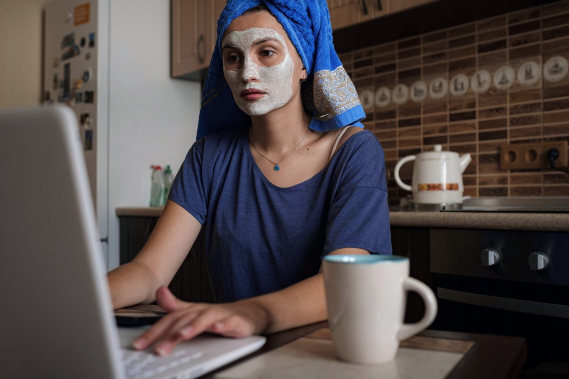 Фото женщины с маской на лице, которая печатает на ноутбуке
