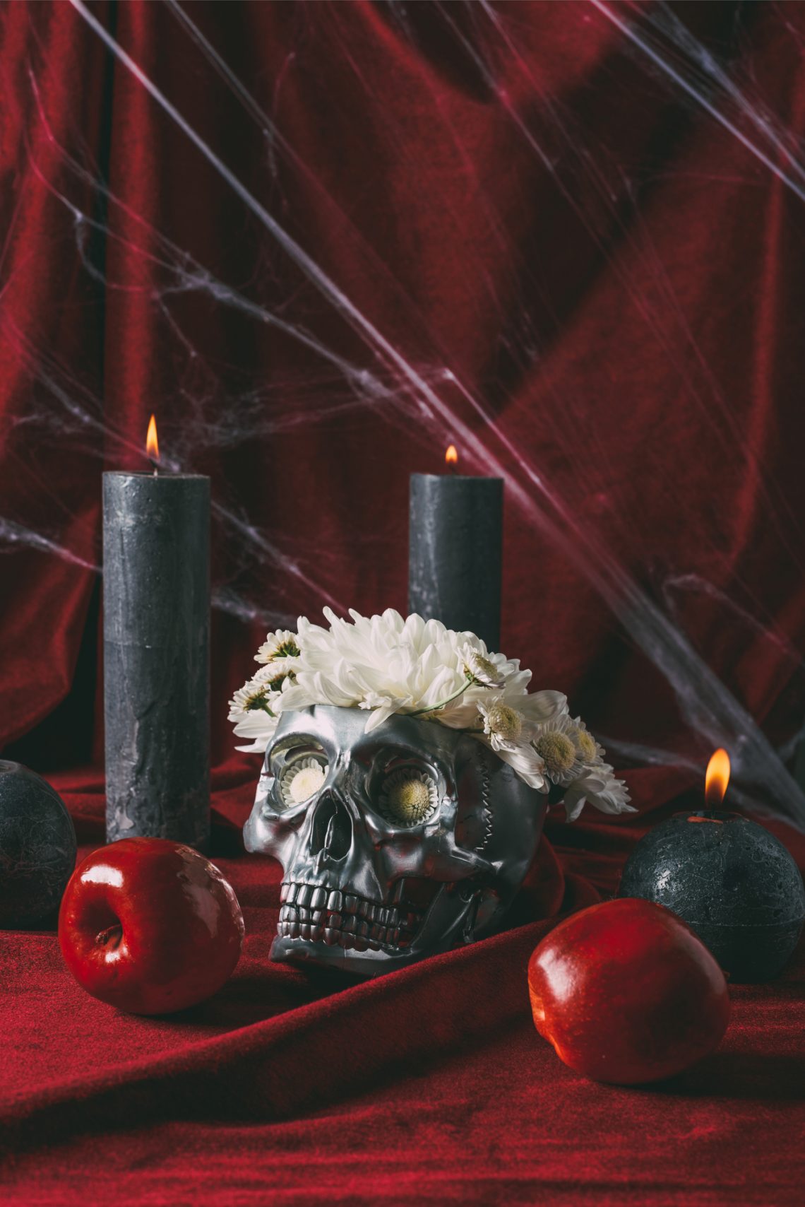 Фото черепа в венке из цветов со свечами, яблоками и паутиной