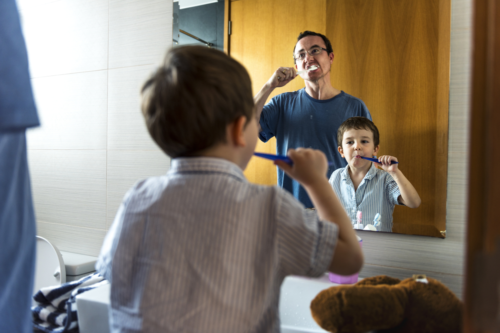 Фото батько і син чистять зуби у ванні