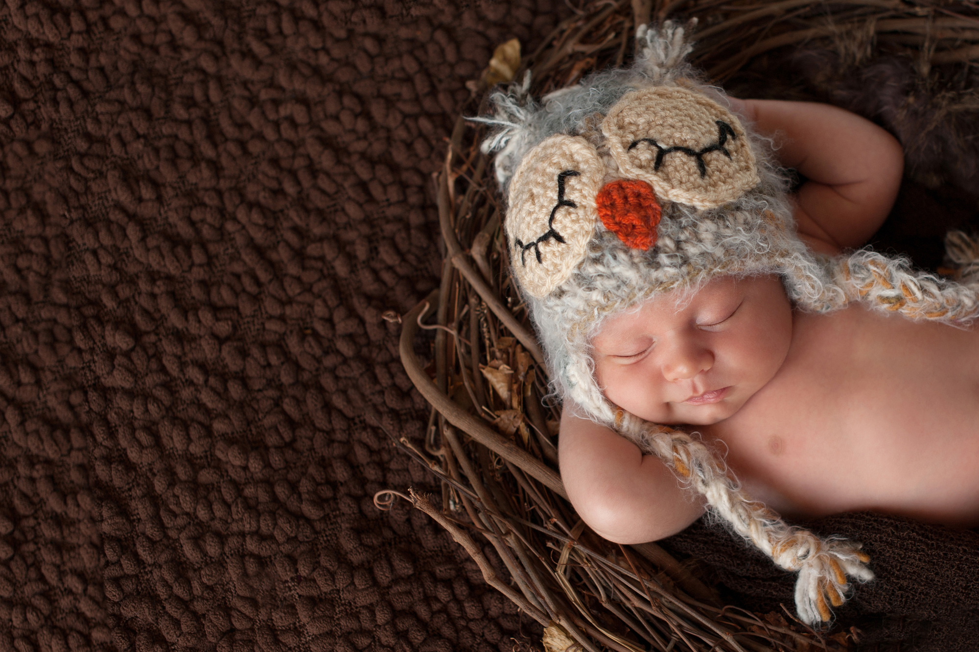 Фото немовля у шапці лежить у гнізді