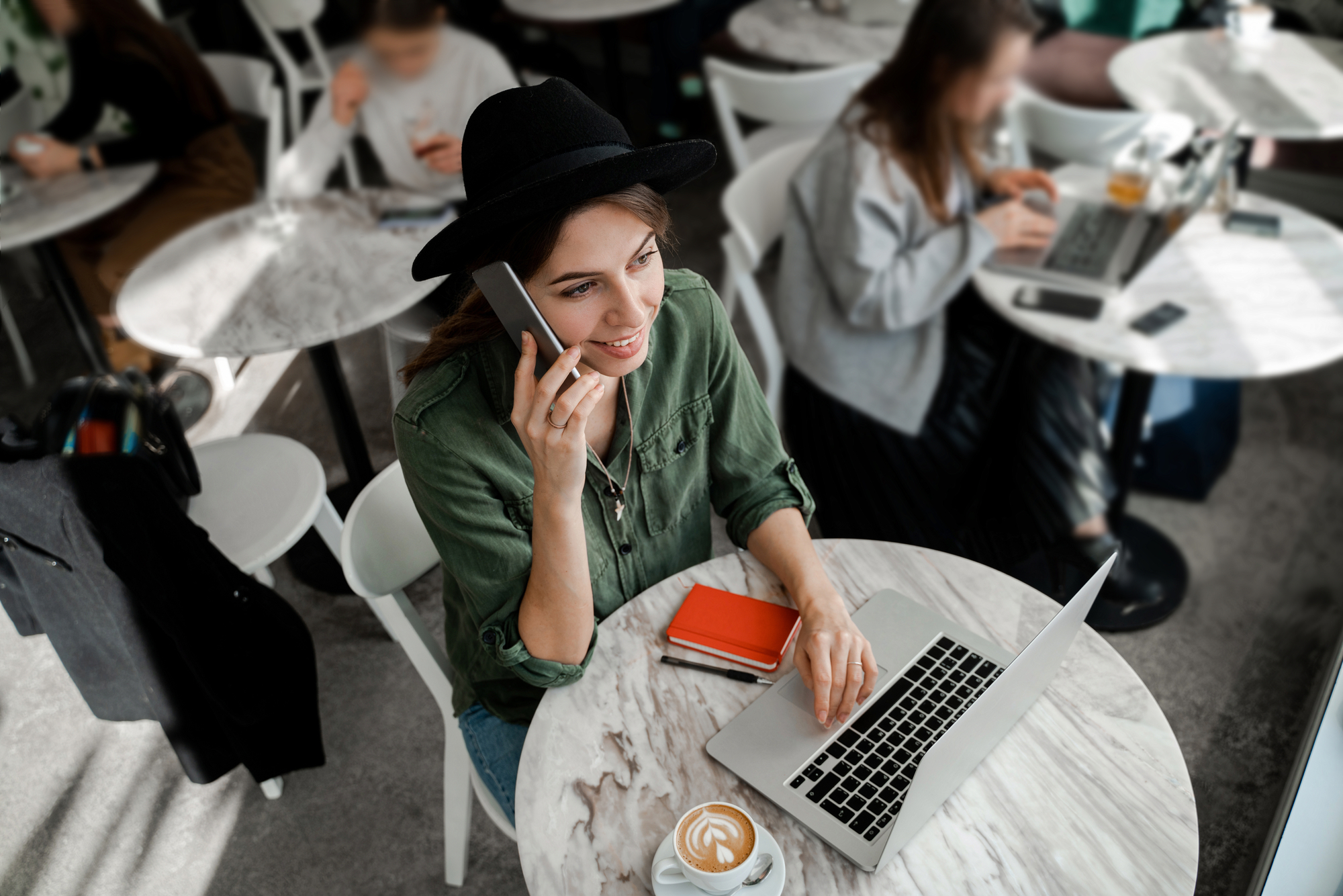 Фото дівчина з ноутбуком і телефоном у кафе