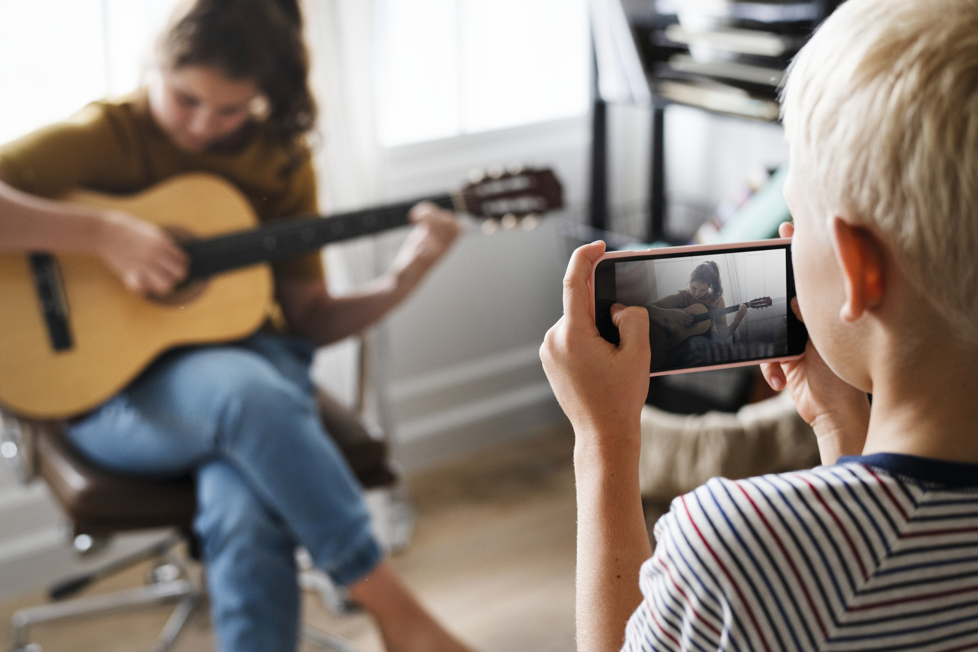 Фото хлочик записує на відео дівчину, яка грає на гітарі