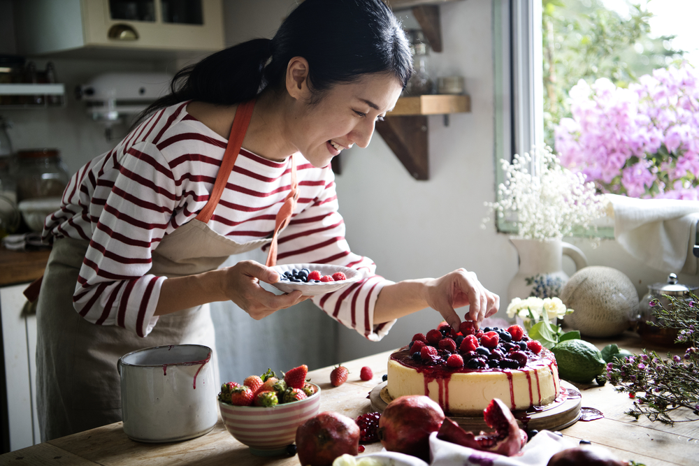Фото жінка прикрашає торт ягодами