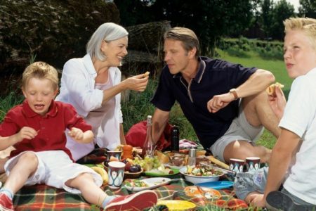 Family enjoying picnic meal. © Depositphotos