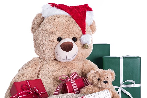 Teddy bear wearing Christmas hat with gifts isolated on white ba