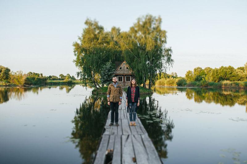 Couple standing on wooden bridge of river