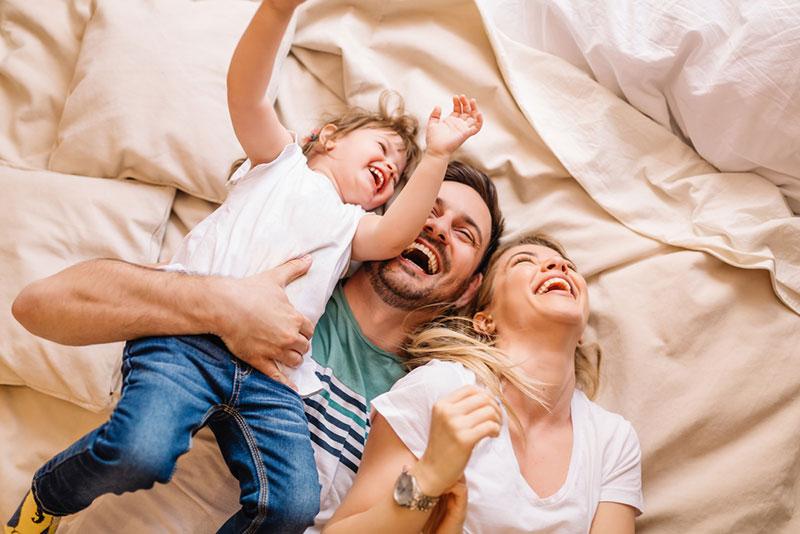 Nebojsa Tatomirov stock photography - Happy family lying on bed and having fun in bedroom