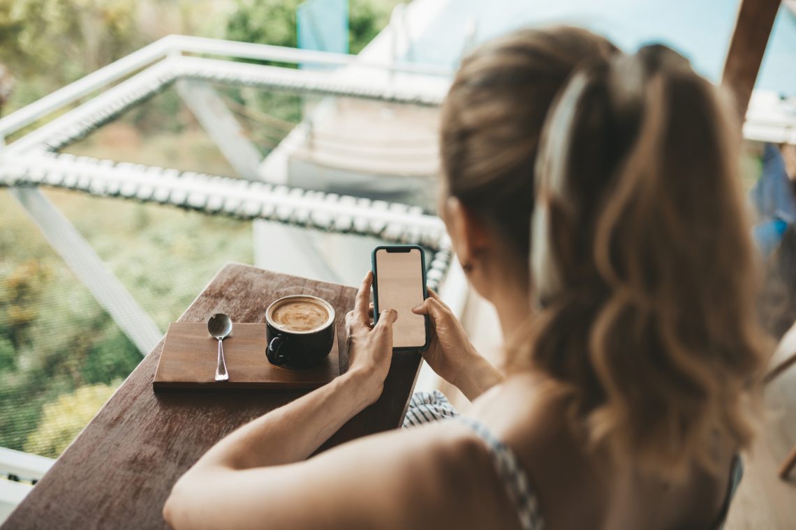 stock photo Blonde woman drinking coffee in a cafe using smartphone