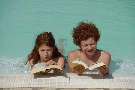 Redheaded girl and boy in swimming pool stock image