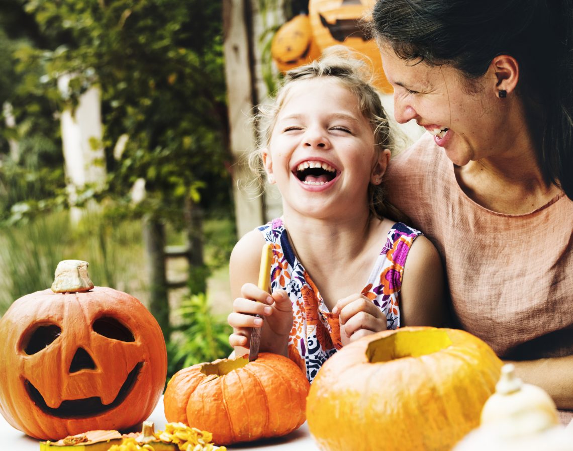 Young cheerful girl carving pumpkins with her mom stock image