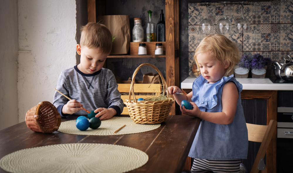 Фотографія хлопчик і дівчинка розмальовують яйця на Великдень