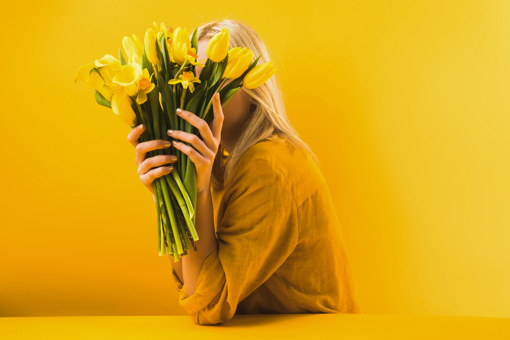 Фотографія жінка з жовтими квітами на жовтому фоні