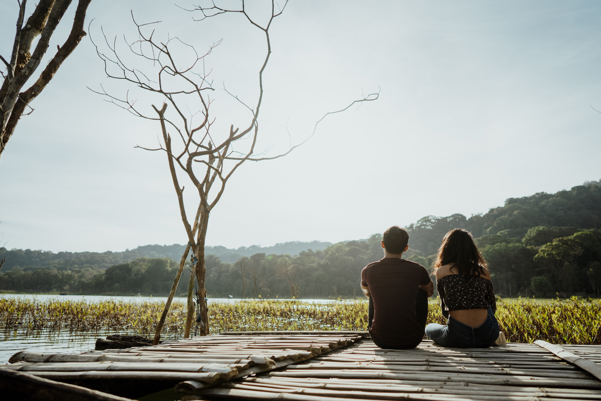 Casal sentado em uma tábua de madeira flutuante em um lago