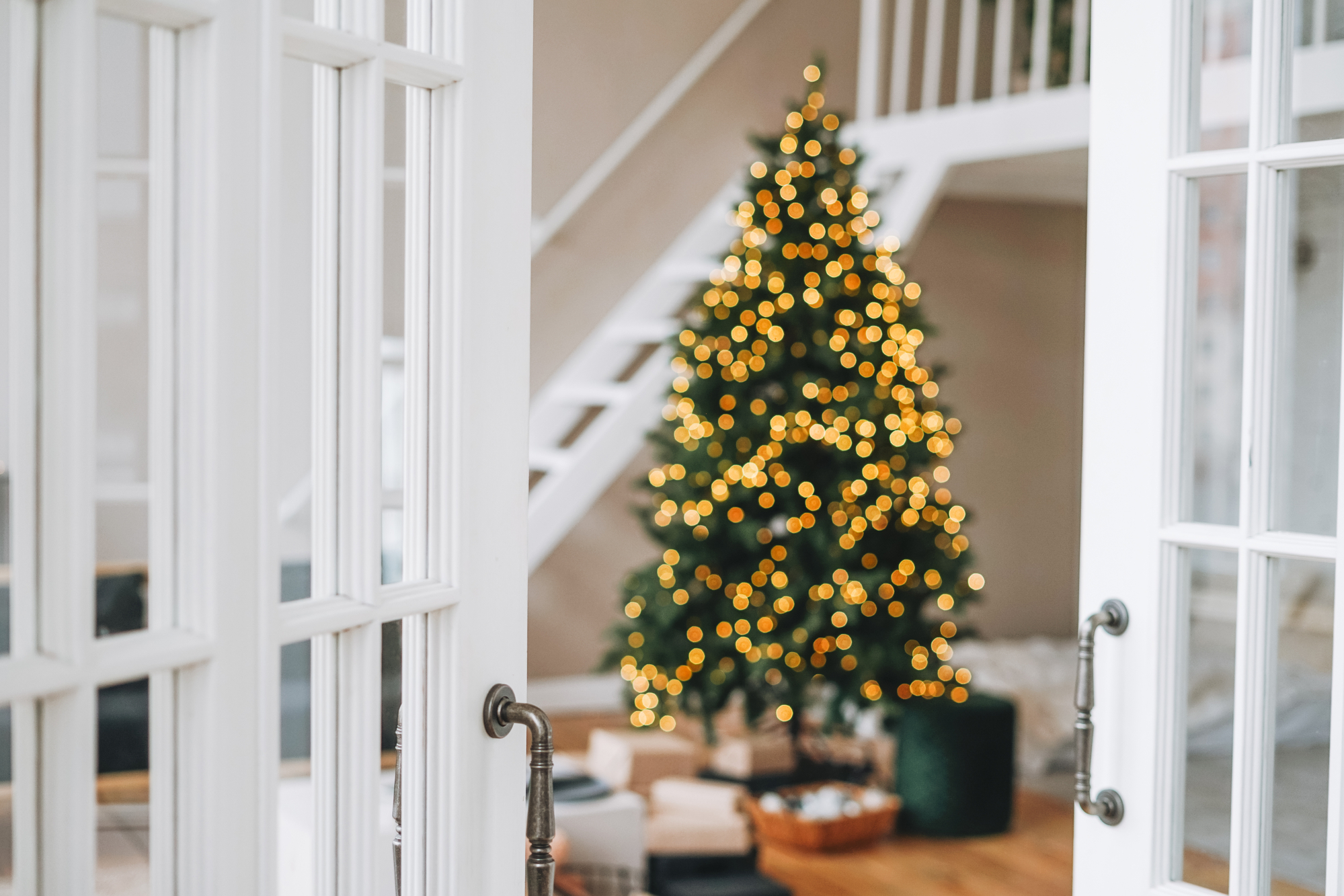 Árvore de Natal decorada borrada com caixas de presente da porta branca no interior brilhante em casa