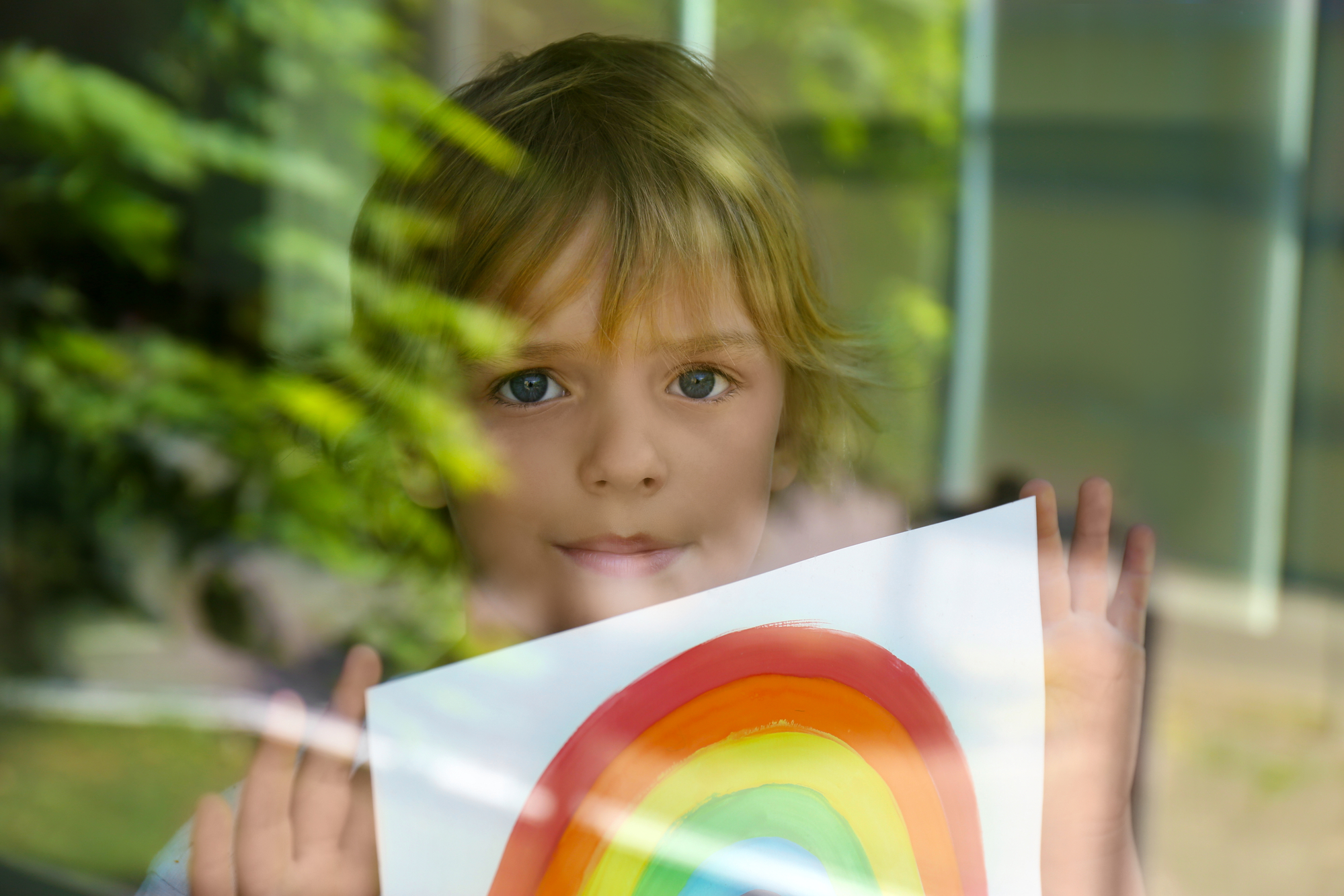 Little boy with picture of rainbow near window - portrait photography ideas