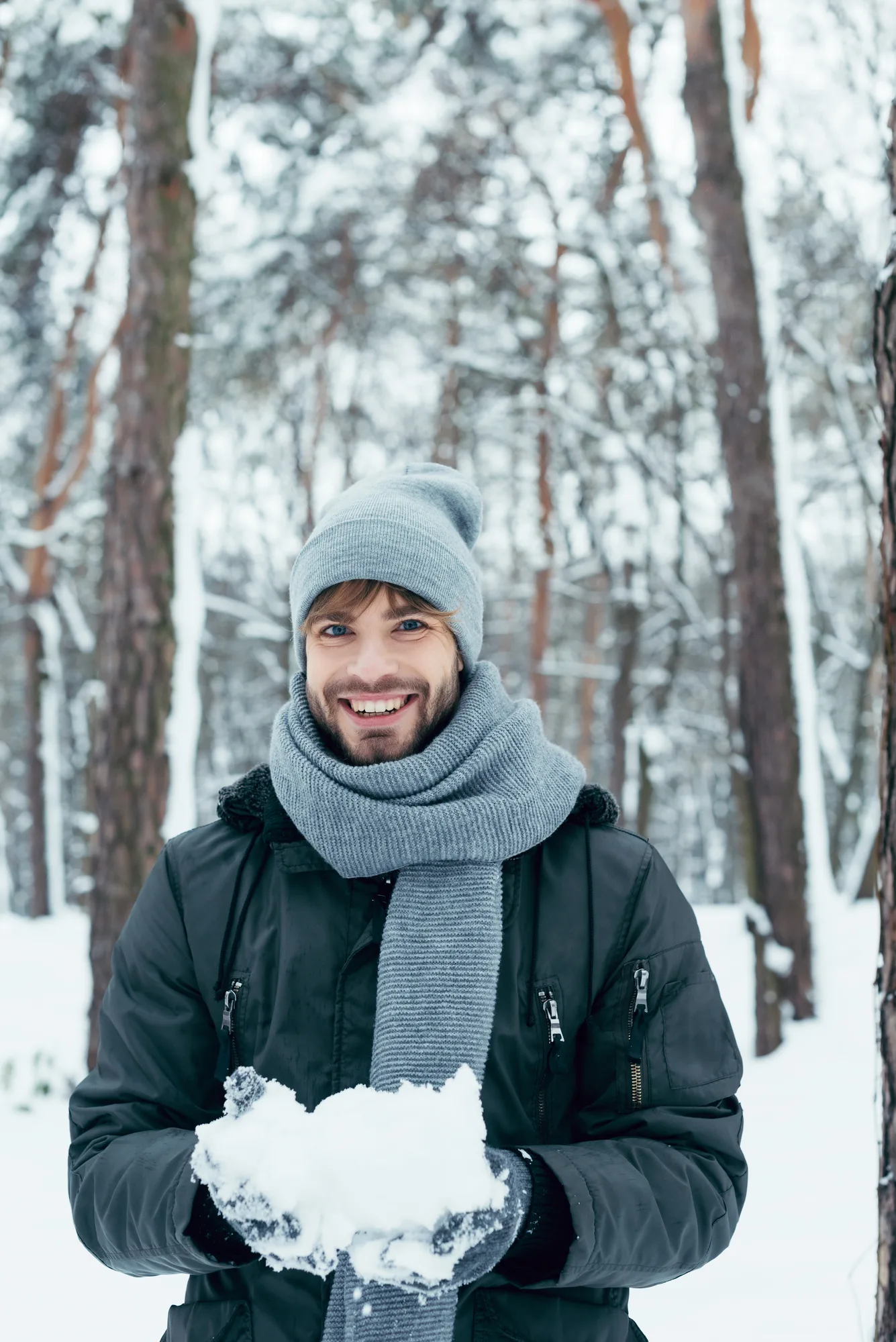 Portrait of happy young man playing with snow - stock images