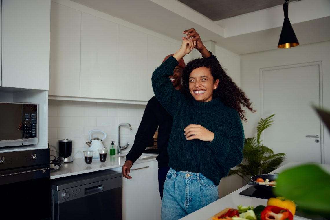 Mixed race couple having fun in the kitchen. Mixed race couple dancing together