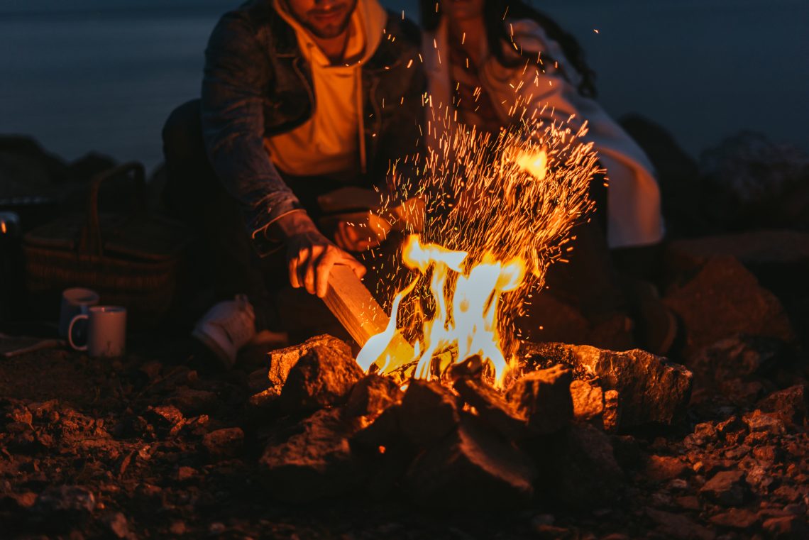 man putting log in a fire