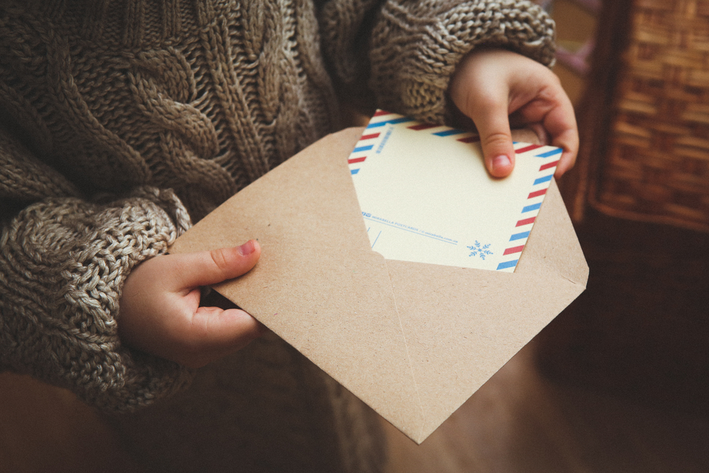 Фотографія дитина кладе листівку у конверт