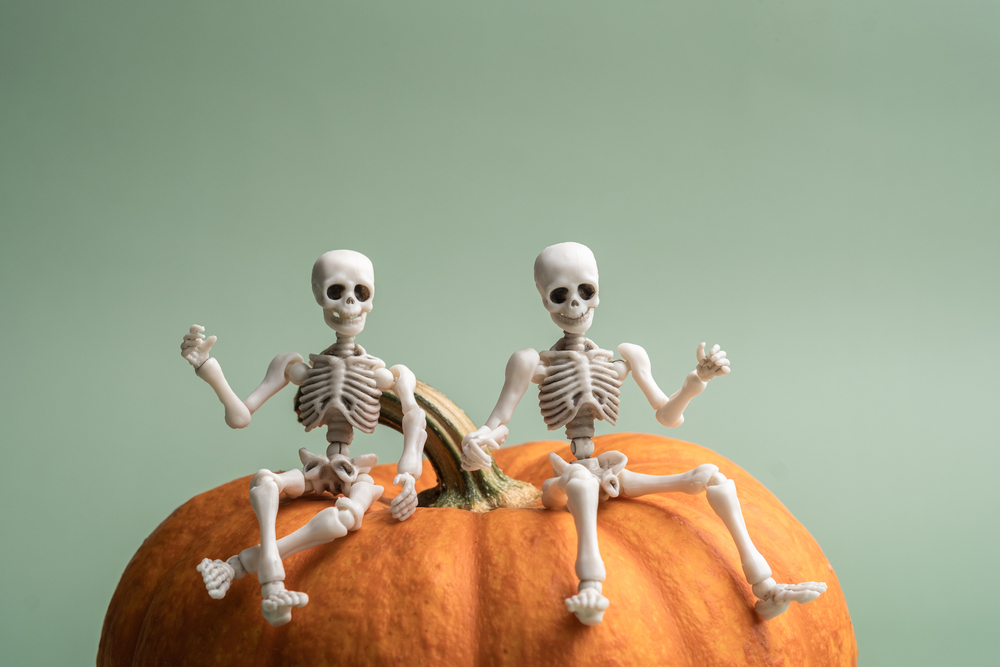 Фотографія іграшкові скелети сидять на хелловінському гарбузі