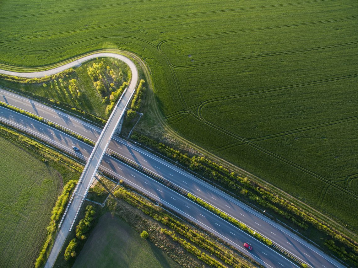 Aerial view of a highway amid fields with cars on it