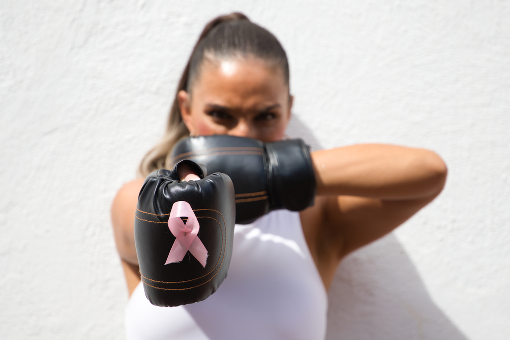 Фотографія жінка у боксерських рукавичках із рожевою стрічкою - символом боротьби проти раку грудей