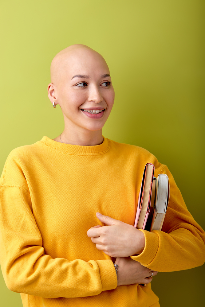 Фотографія портрет лисої жінки у жовтому светрі з книгами