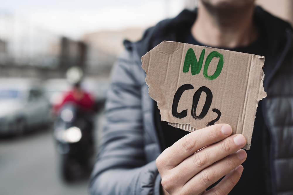 Фотографія чоловік тримає шматок картону з написом NO CO2