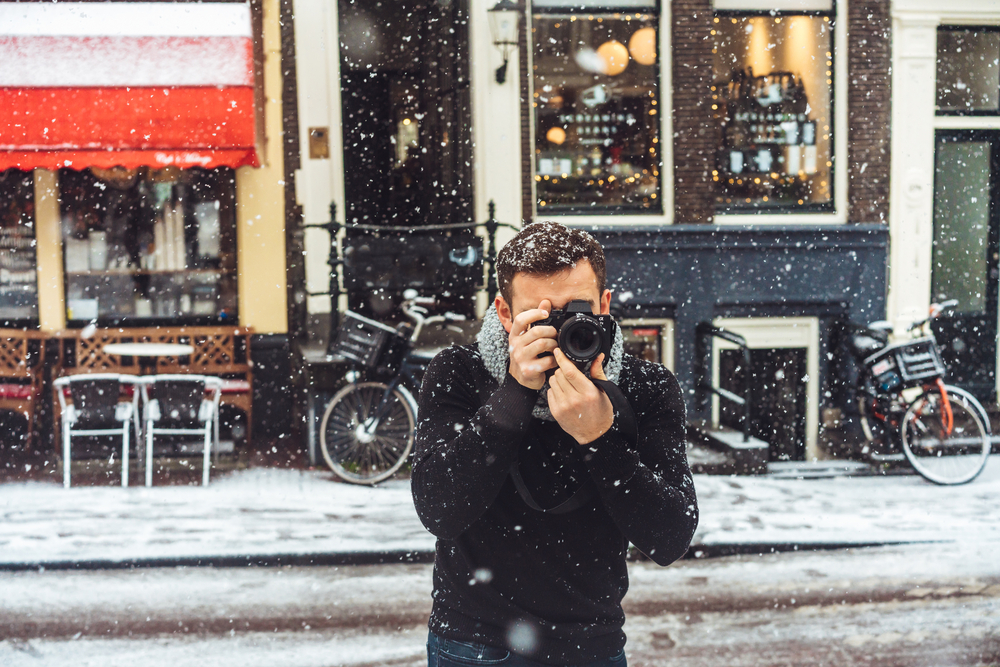 Фотографія чоловік з камерою знімає на засніженій вулиці