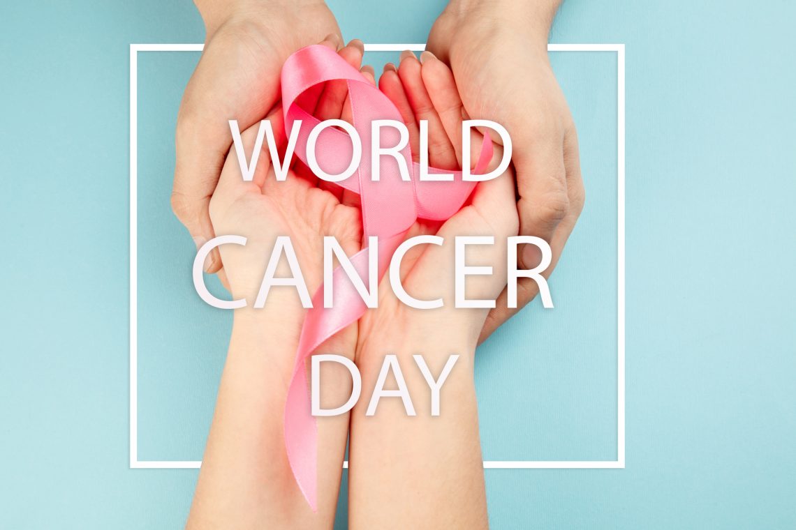the text world cancer day and a pink ribbon on a table background