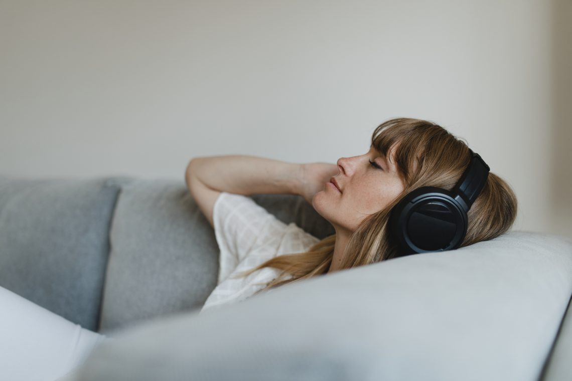 Woman listening to music during coronavirus quarantine on a cou