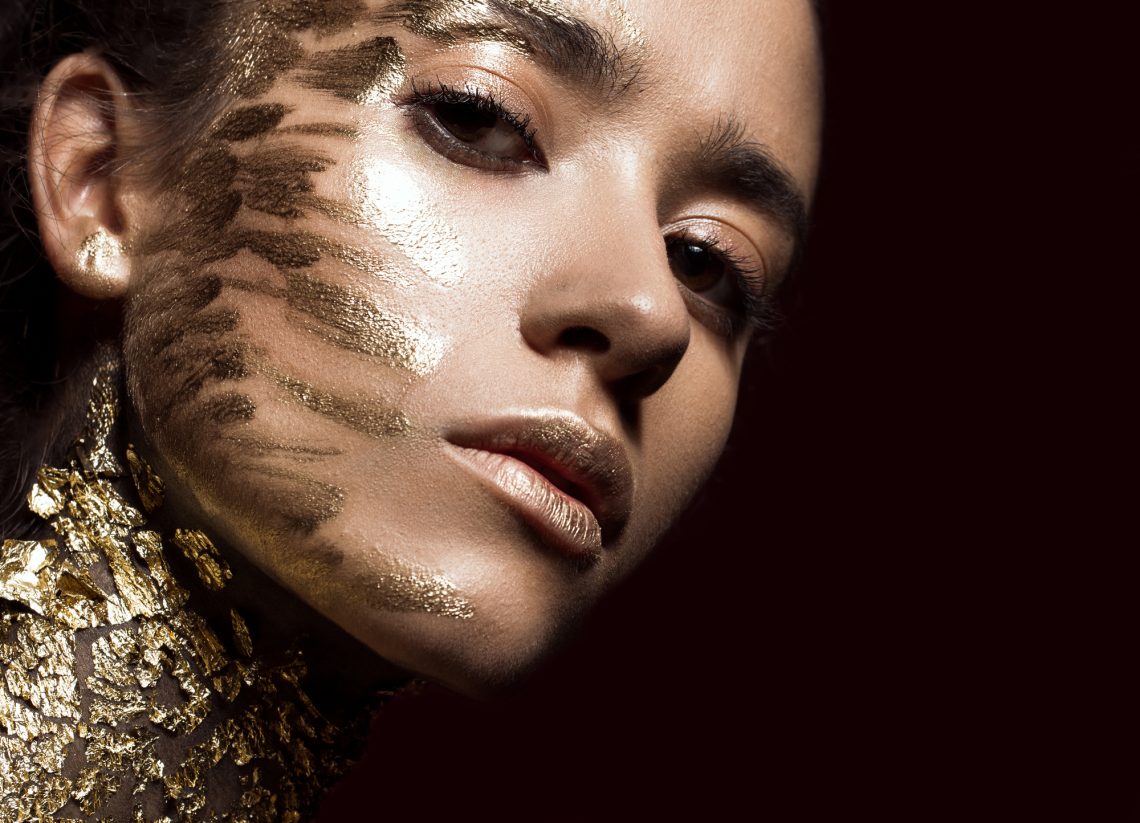 Beautyful girl with gold glitter on her face. Art image beauty