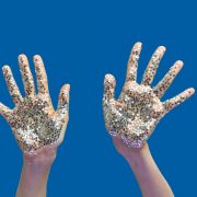 Woman's hands with bright silver glitter stars on a blue