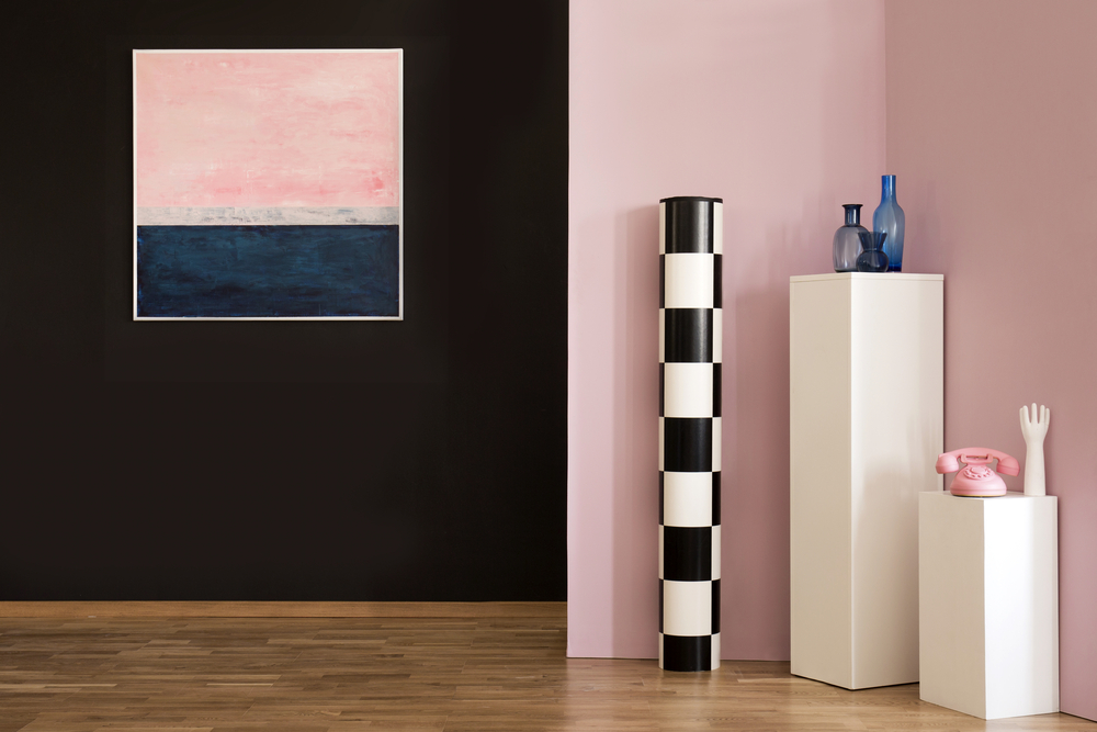 Blue and pink painting on black wall in flat interior with phone on pedestal