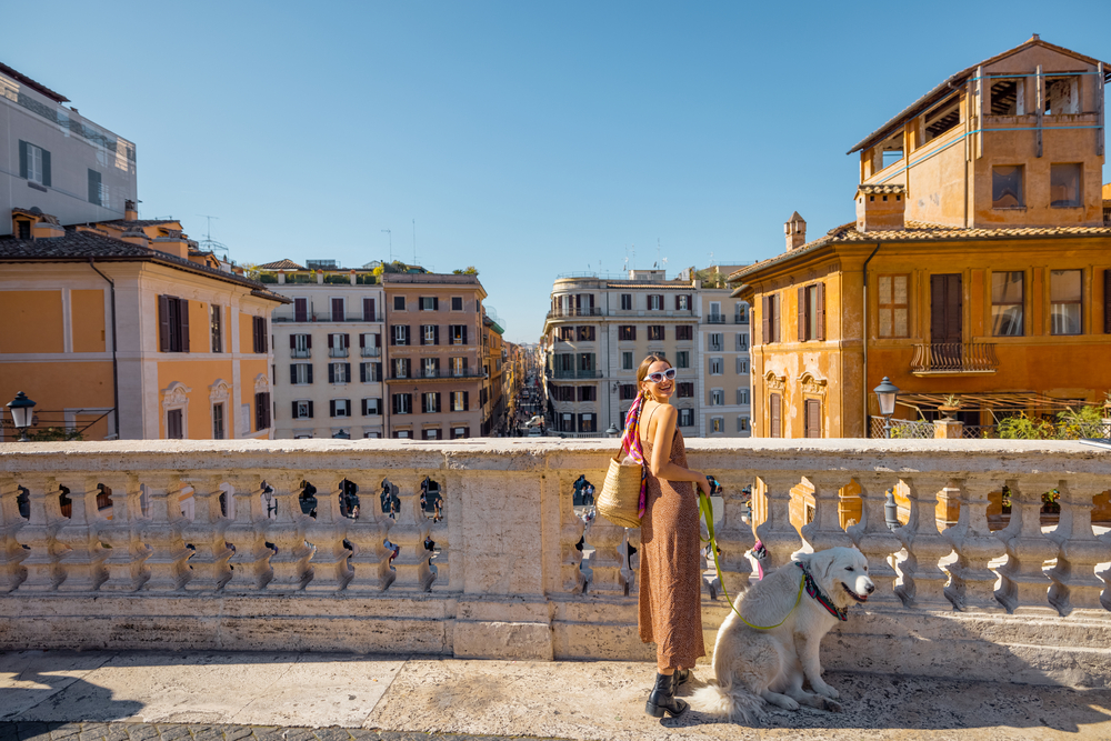 Woman walks with her dog. A beautiful cityscape of Rome on the background 