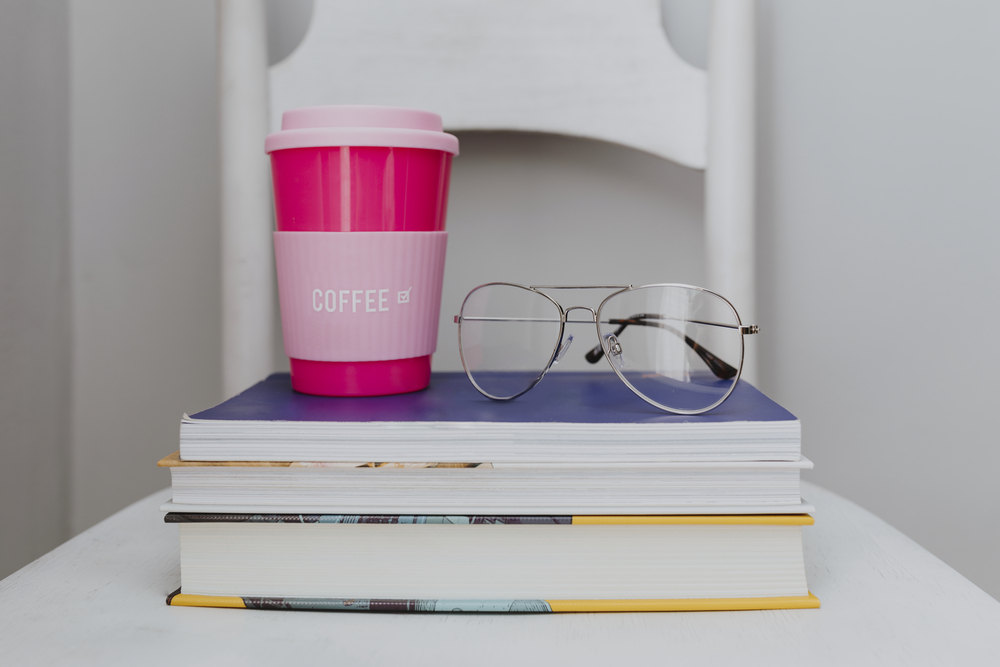 Pink travel mug on a stack of textbooks