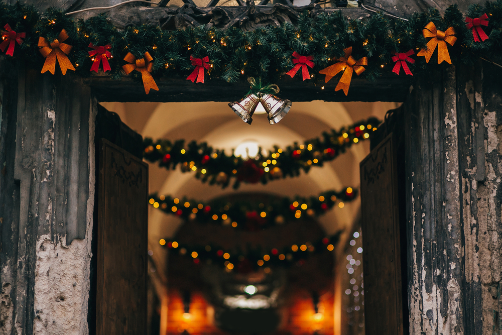Фото стильні різдвяні прикраси, дзвіночки, гірлянди, ялинові гілки з орнаментом на фасаді будинку на вулиці європейського міста