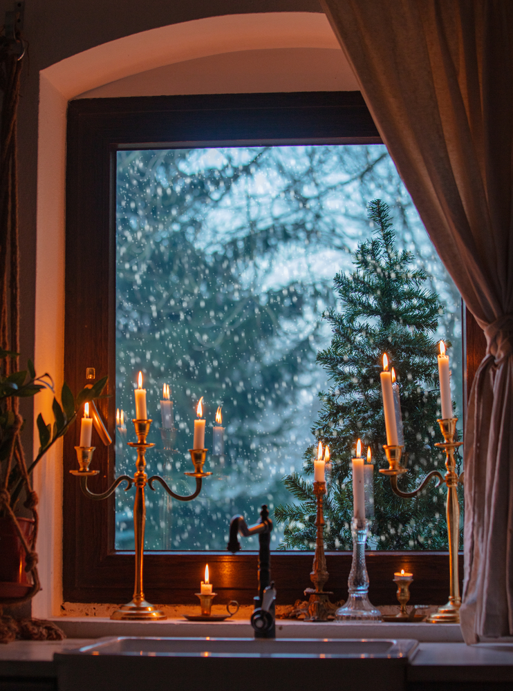 candles on the window in kitchen during a snowfall, trees on the