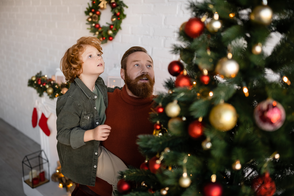 Фото батько із сином прикрашають різдвяну ялинку