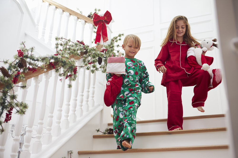 Фото Двоє дітей на сходах у піжамах з різдвяними панчохами