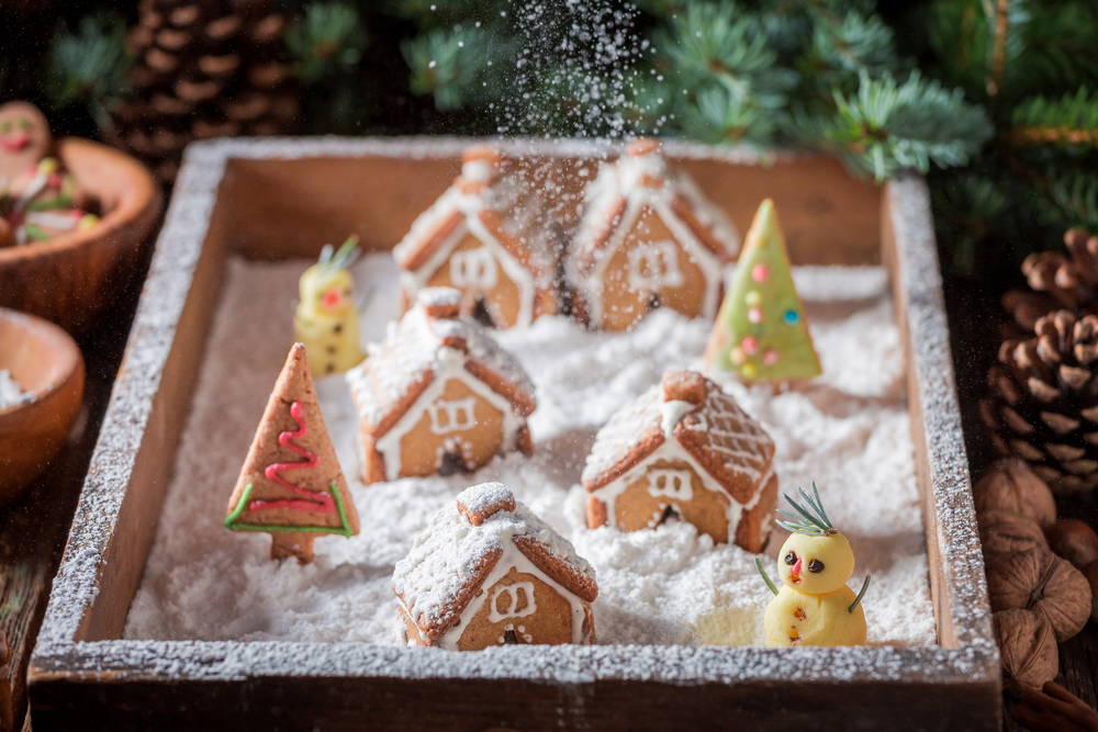 Falling snow to Christmas gingerbread village with snowman and trees