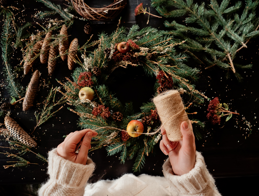 Woman in white sweater making a Christmas wreath