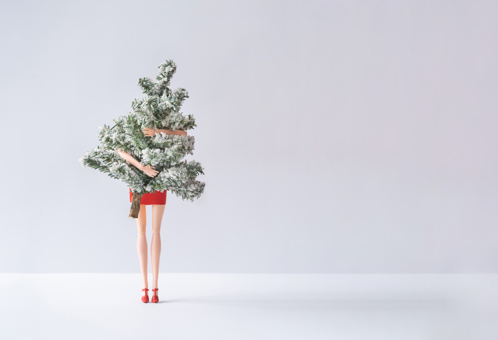 Girl in red dress holding snowy Christmas tree. Minimal winter h