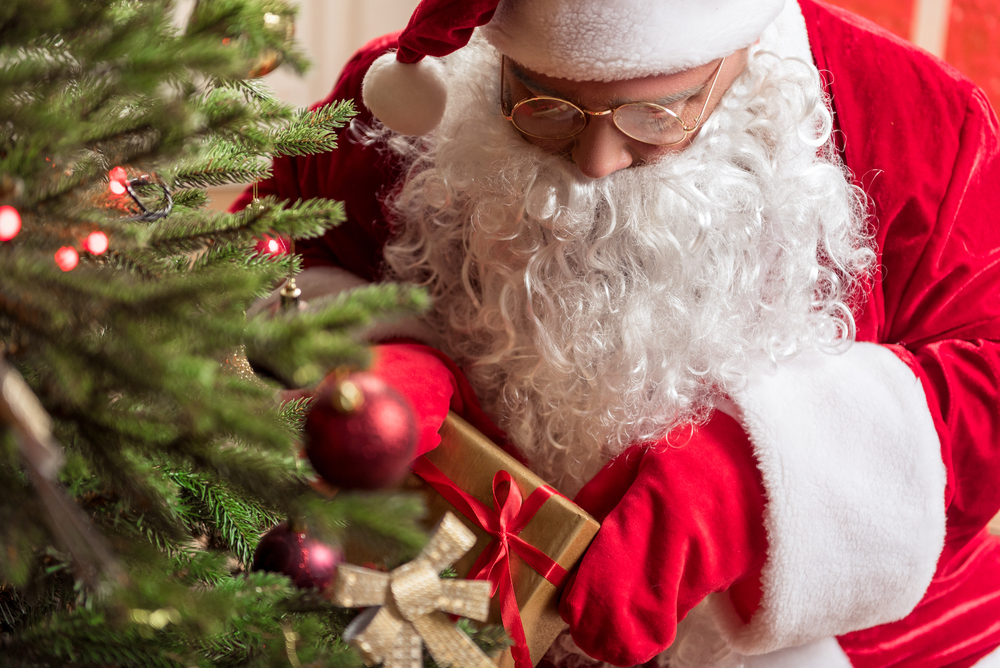 Secretive Santa Claus laying gift box to fir tree
