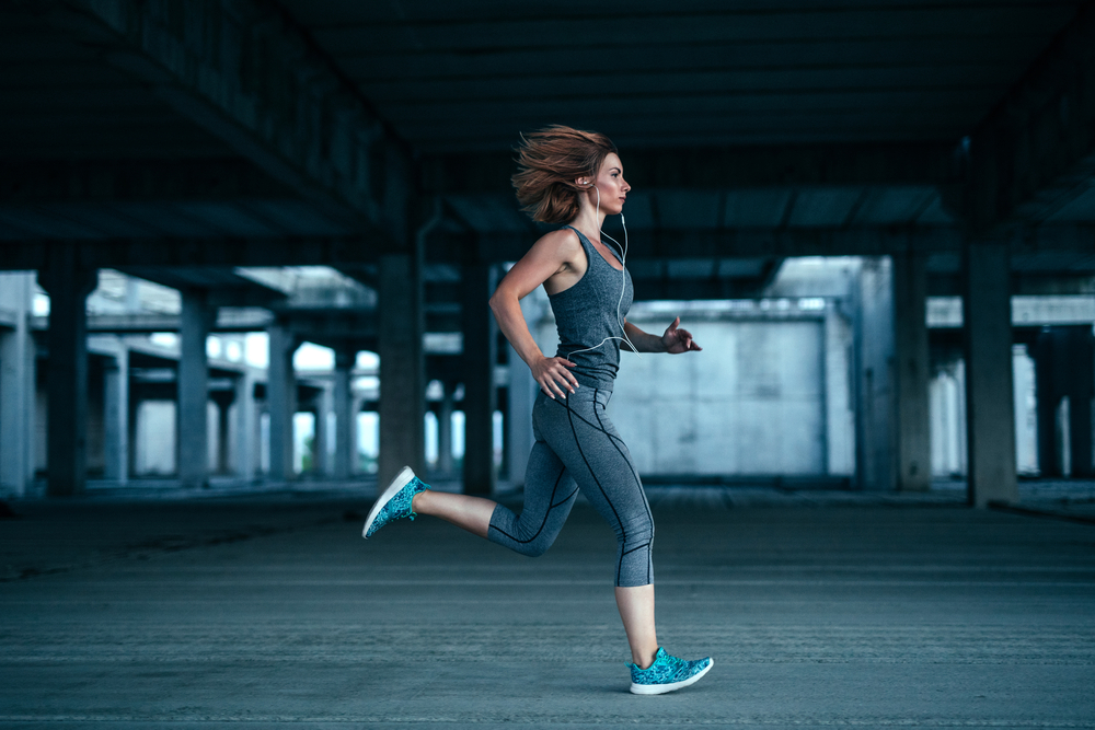 Фото молодої жінки-спортсменки, яка біжить у старій покинутій будівлі 