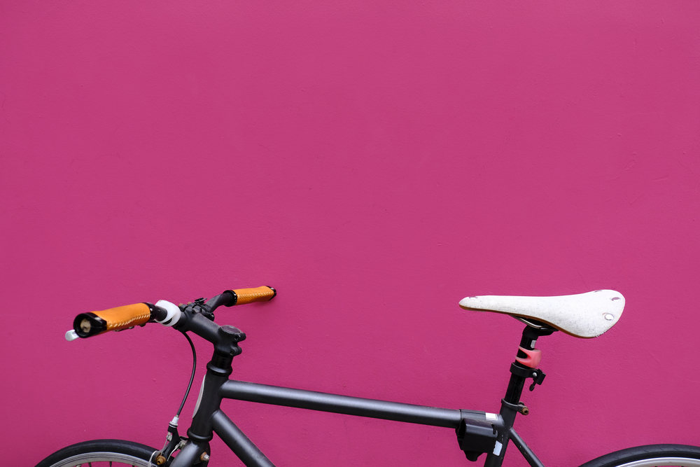 Фото Чорний міський велосипед на рожевому тлі